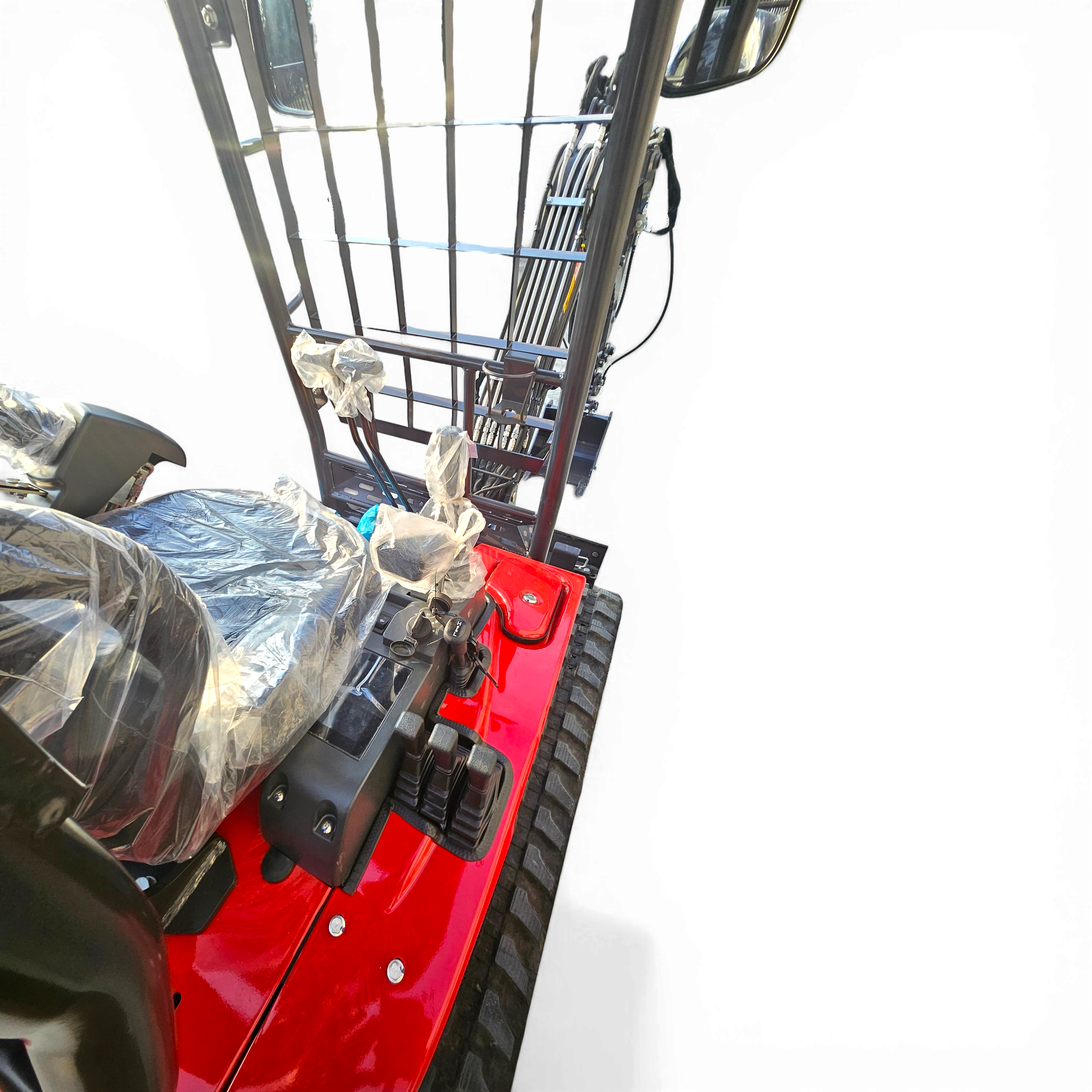 Close-up of a red industrial machine frame with metal bars and exposed controls, some parts wrapped in plastic.
