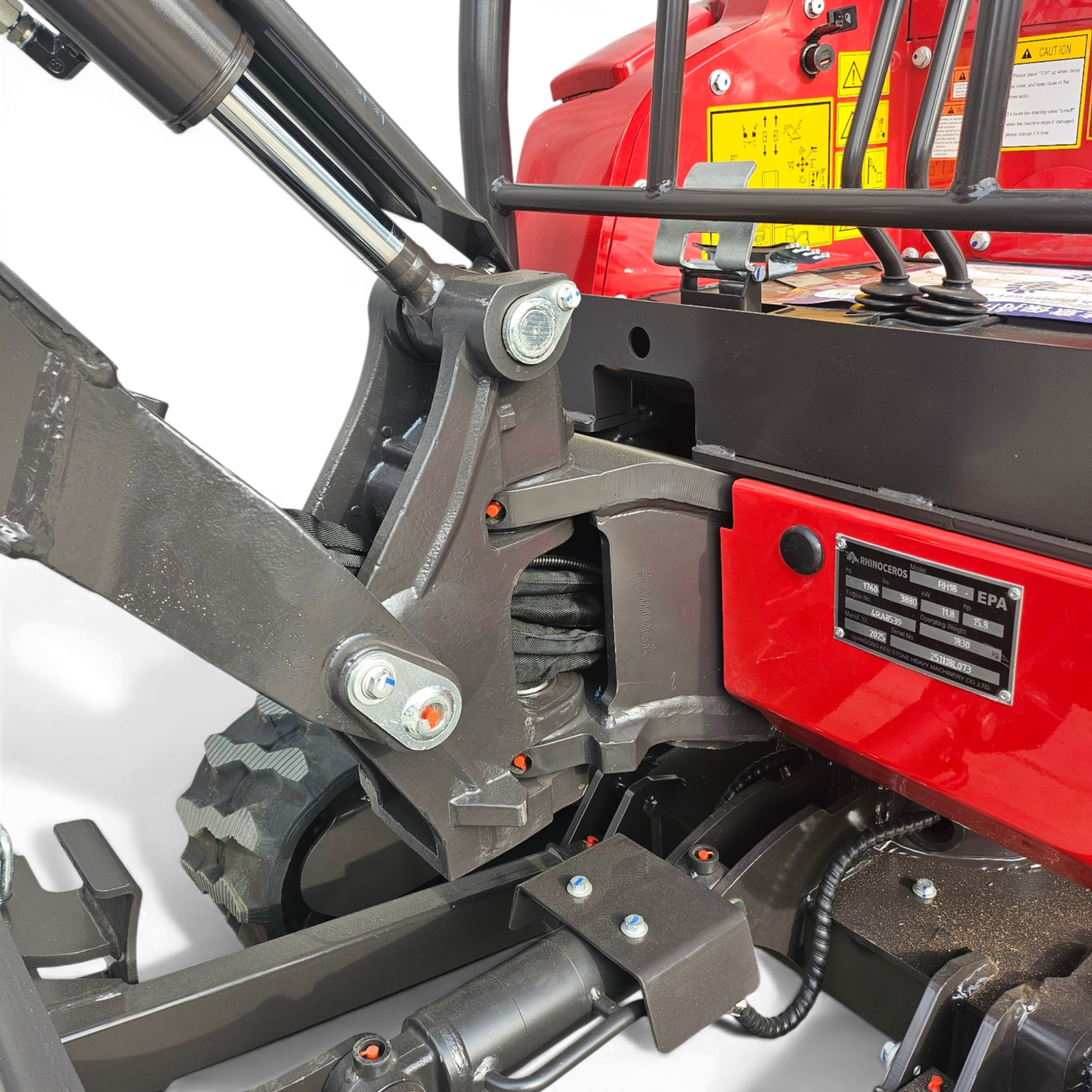 Close-up of a hydraulic actuator and linkages on a red machine, showing bolts, pins, and protective framework.
