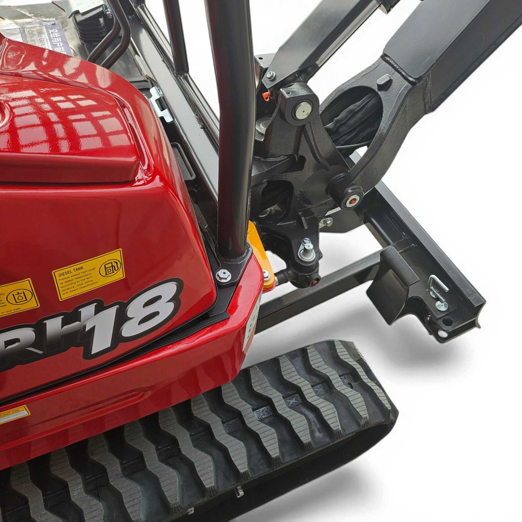 Close-up of a red industrial machine body with a black tracked undercarriage and yellow warning stickers on the side.