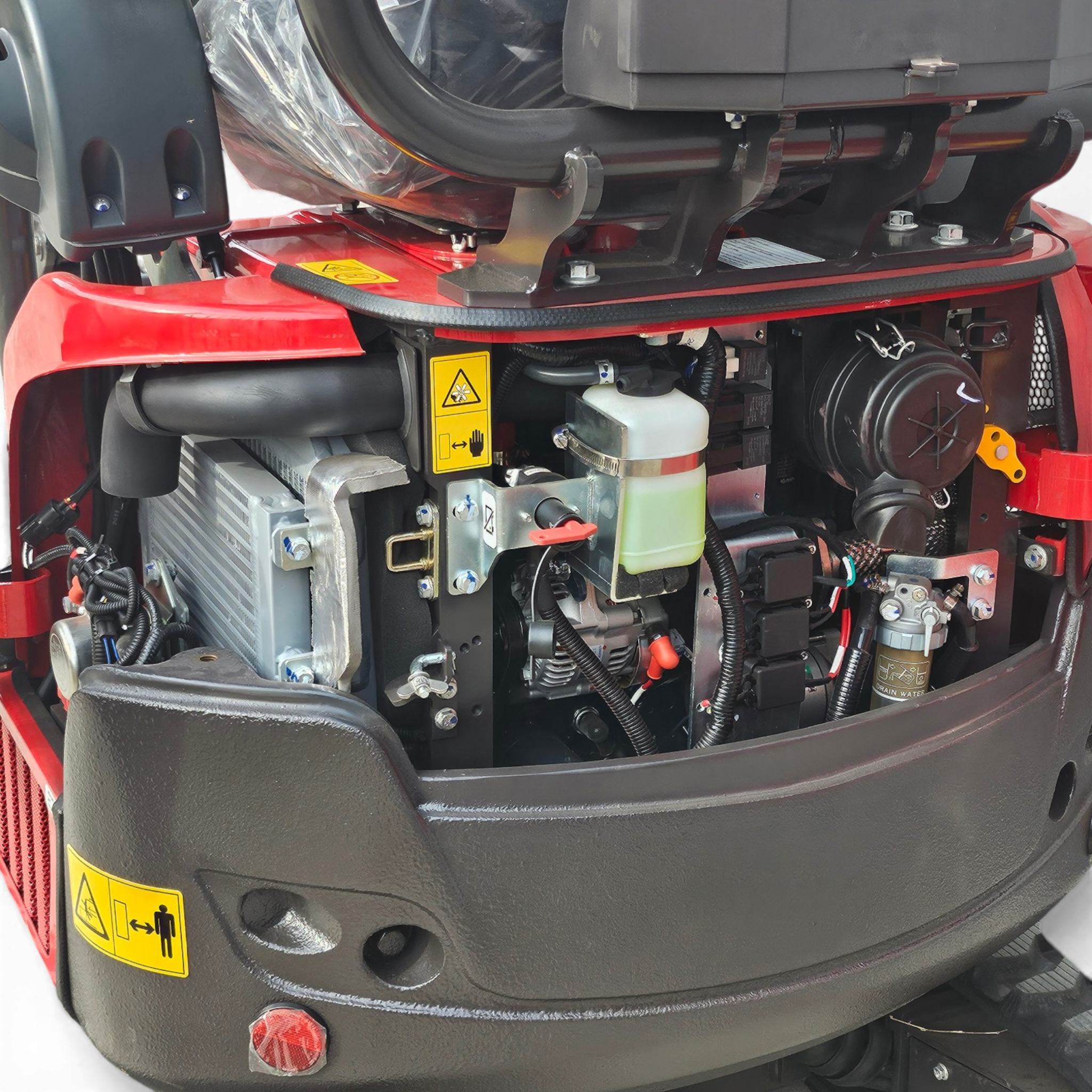 Close-up of a red truck engine bay showing hoses, wiring, metal brackets, and a yellow warning label on the bodywork.