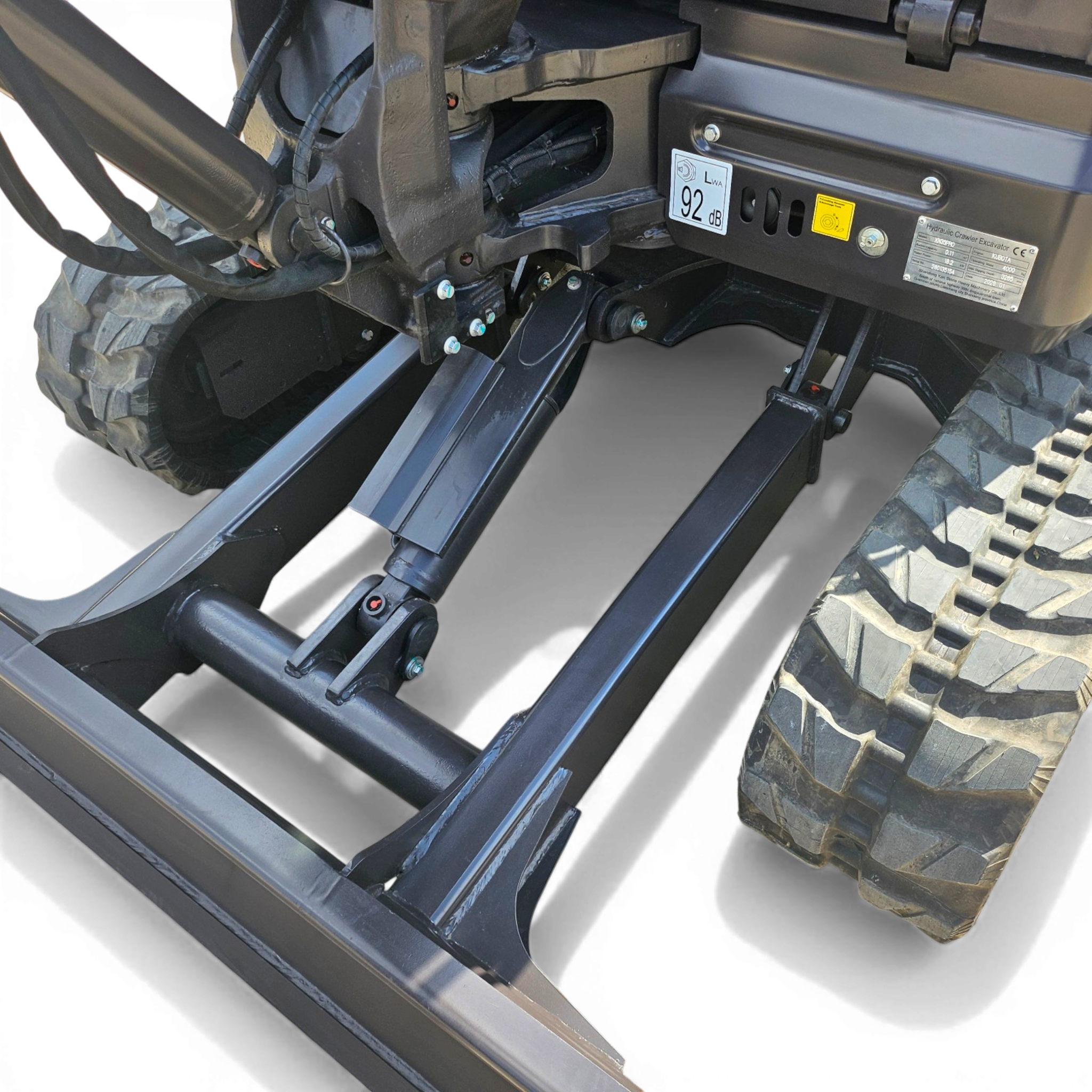 Close-up of a heavy machinery undercarriage showing hydraulic hoses, metal framework, and a large treaded tire area on a construction vehicle.