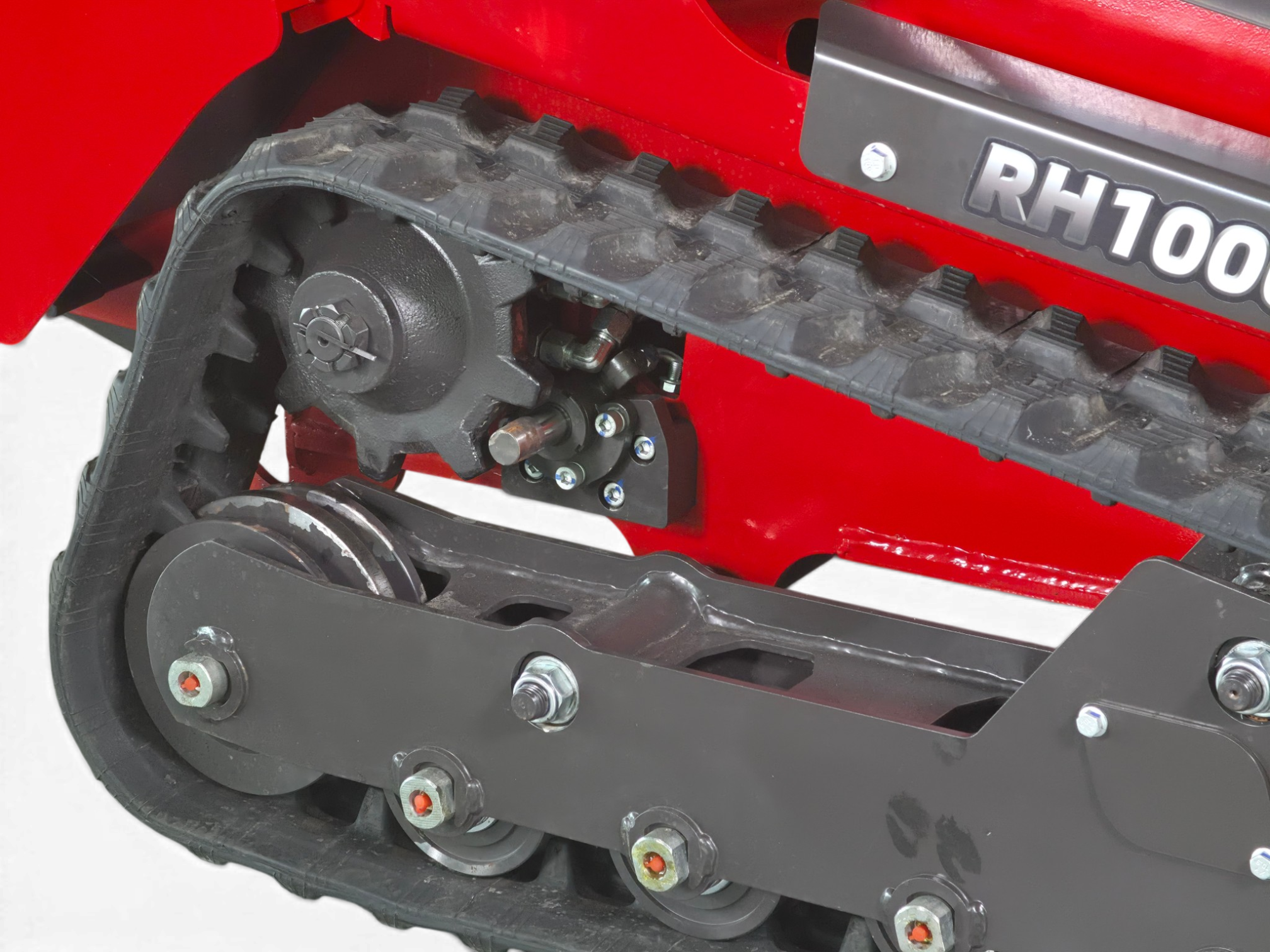 Close-up of a red machine's rubber track and undercarriage, showing the drive wheel, bolts, and tread cleats (RH1000 label visible).