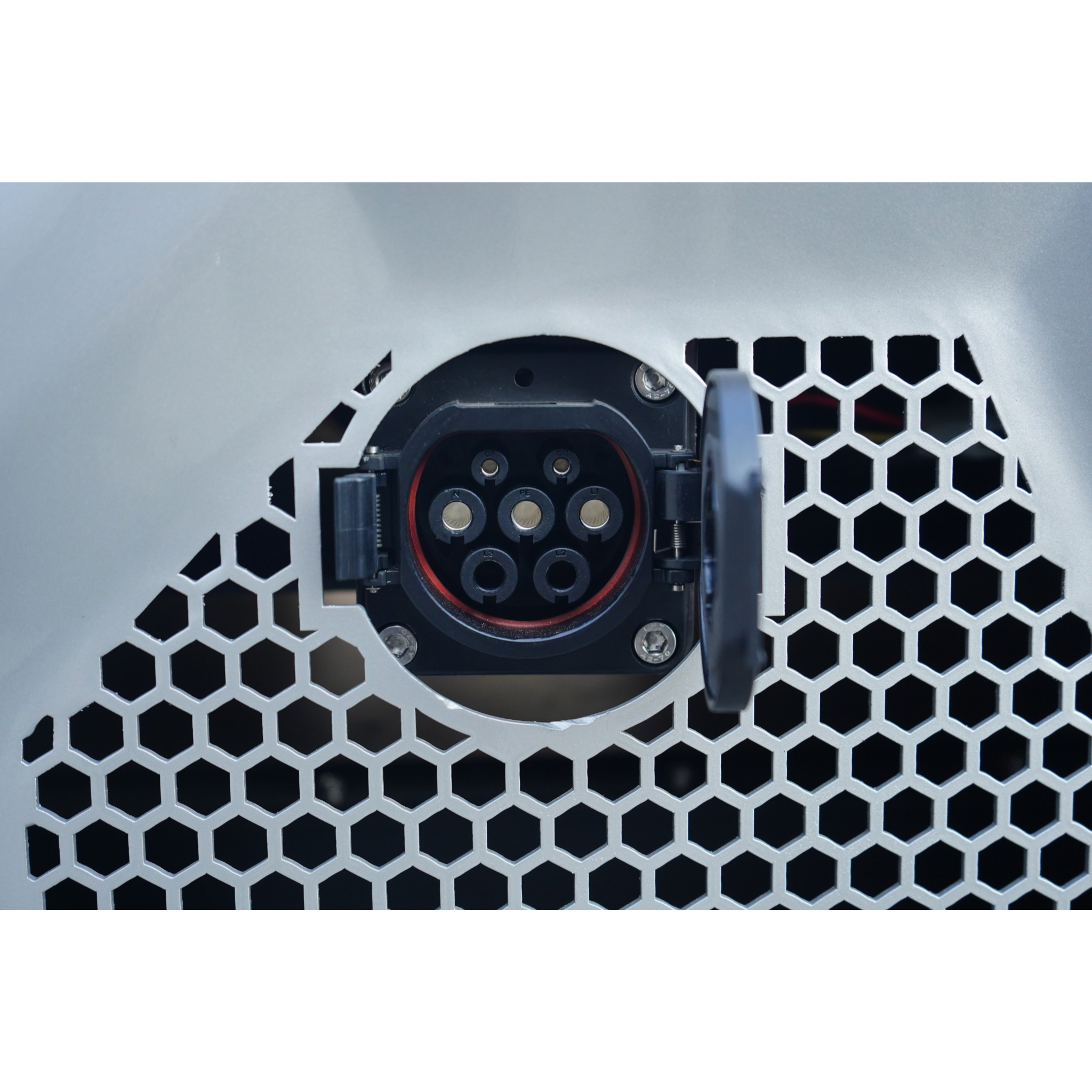 Close-up of a hexagonal metal grille with a circular electrical connector visible behind it.