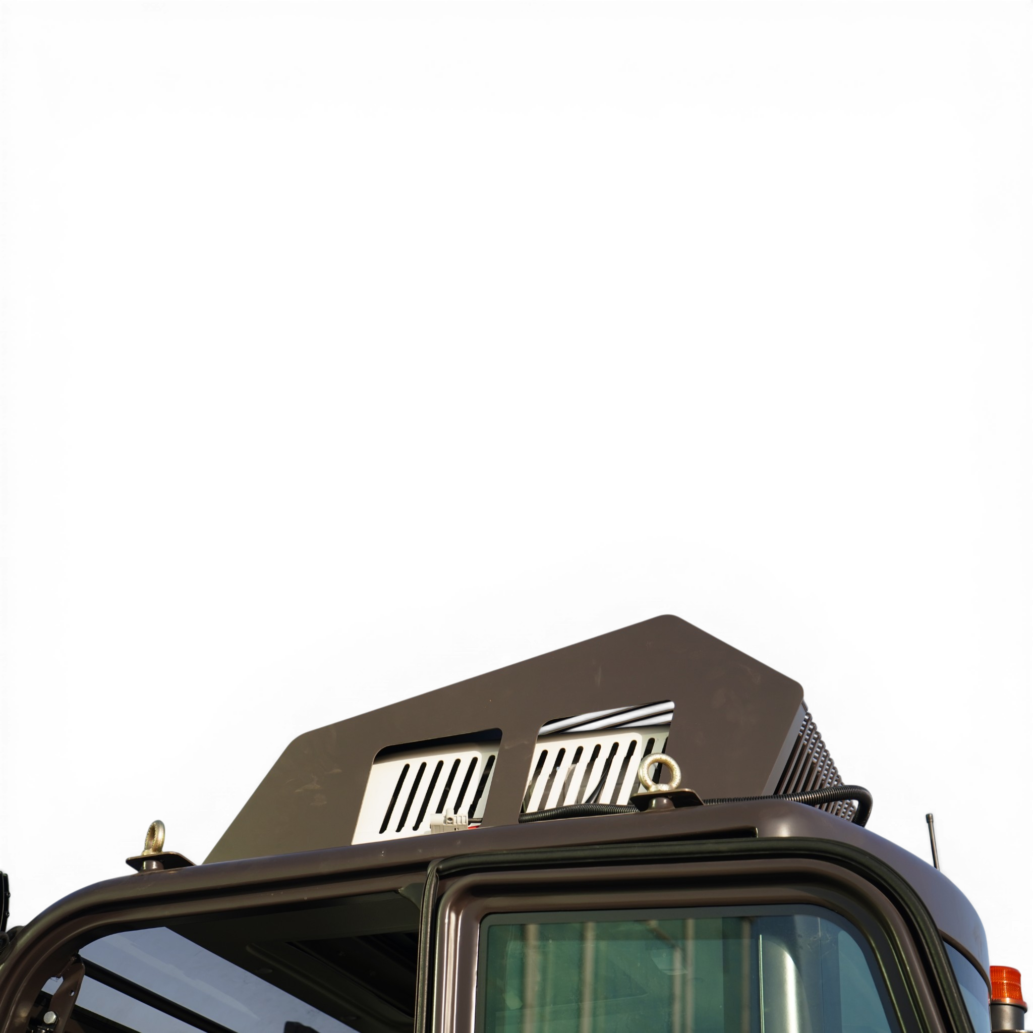 Front corner of a large truck cab, showing the windshield, vented grille area, and an orange signal light on the right edge