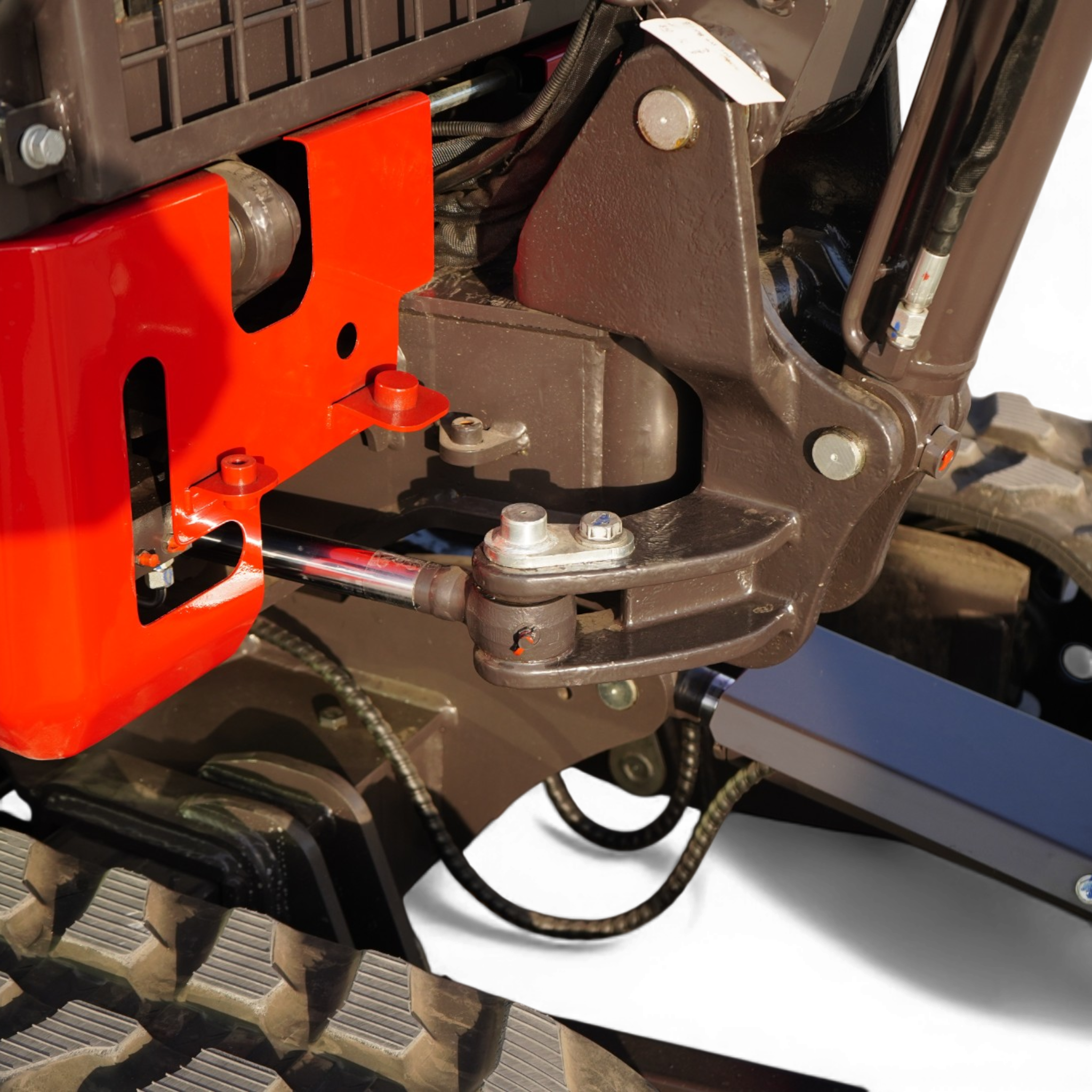 Close-up of industrial machinery showing an orange frame with bolts, connected hoses, and a dark brown housing piece.