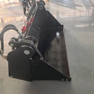 Industrial hydraulic bucket attachment with green hoses and red quick-connect fitting and pivoting joints, mounted on a black metal frame.