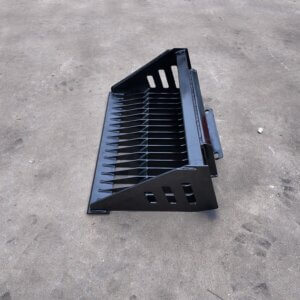 Black metal rake/attachment with evenly spaced tines, resting on a concrete surface.