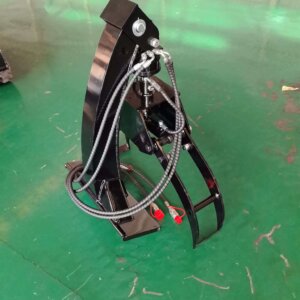 Heavy-duty hydraulic grapple attachment with multiple hoses on a green warehouse floor.