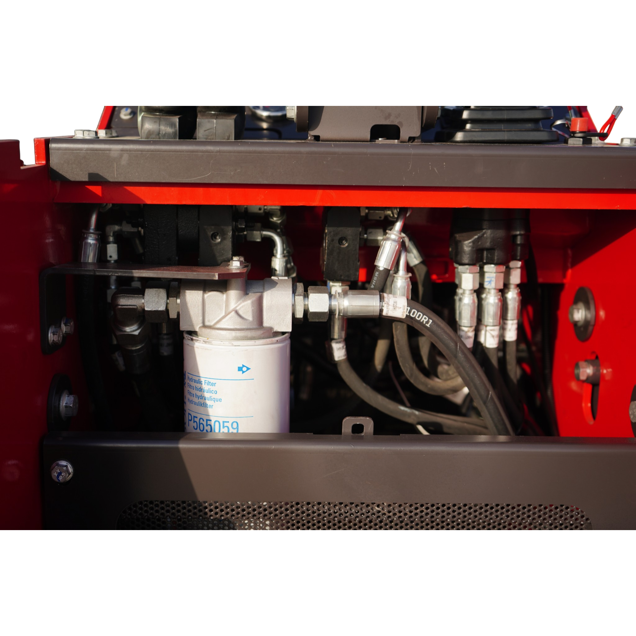 Close-up of an industrial hydraulic system with hoses, fittings, and metal blocks inside a red machine chassis.