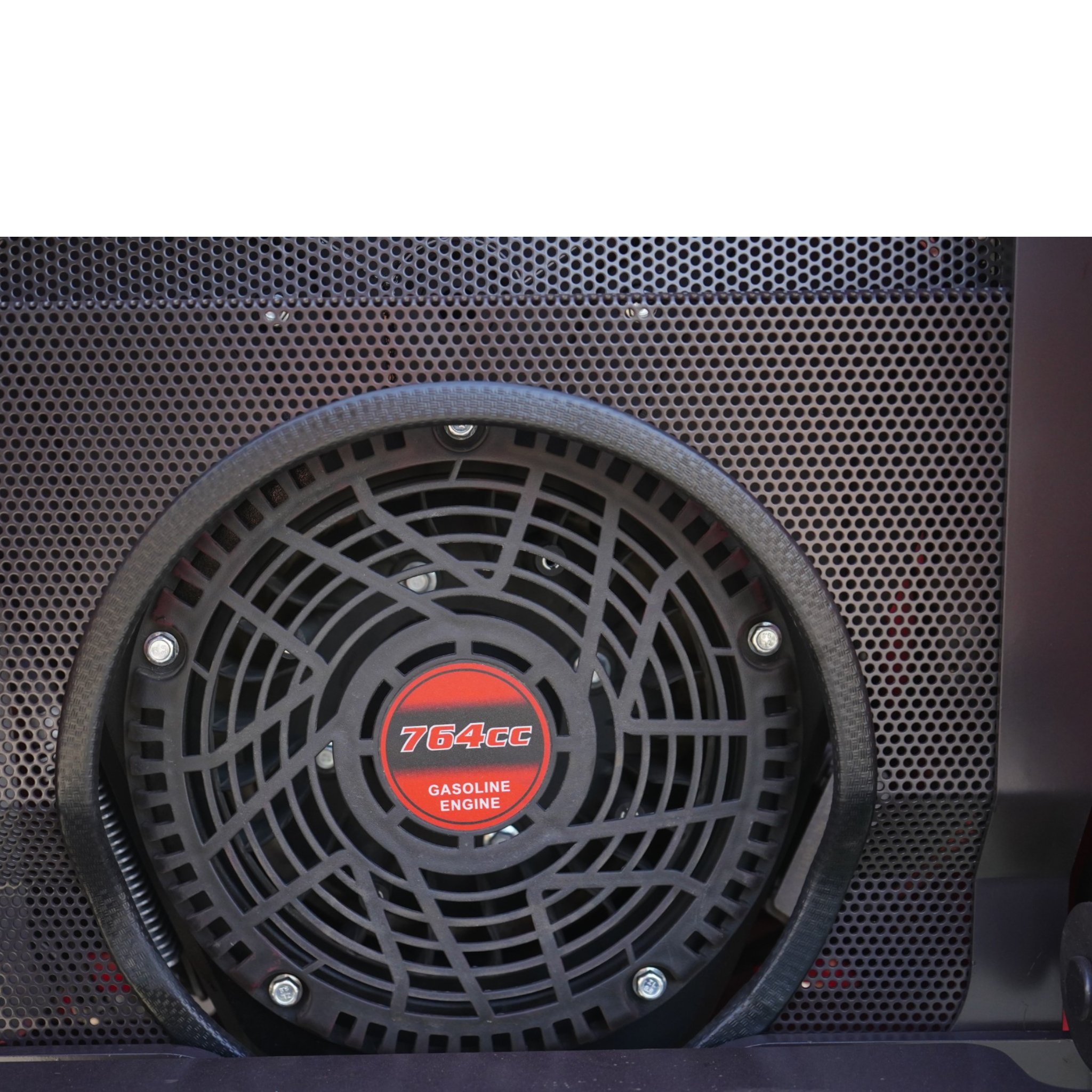 Close-up of a circular car speaker with a black plastic grille and a red center reading '764cc Gasoline Engine' against a perforated metal panel.