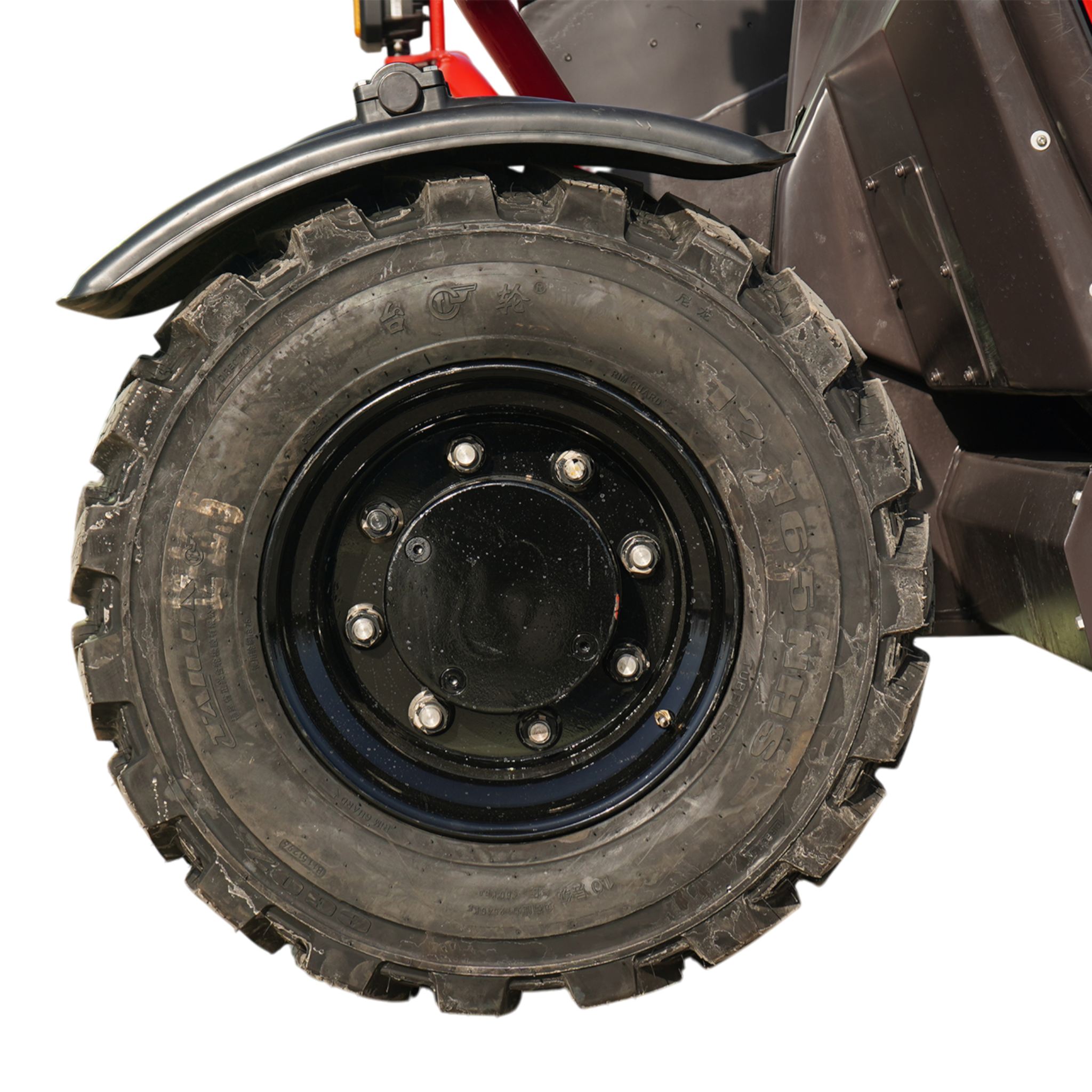 Close-up of a rugged off-road tire mounted on a black rim with a metal mudguard nearby on a vehicle.