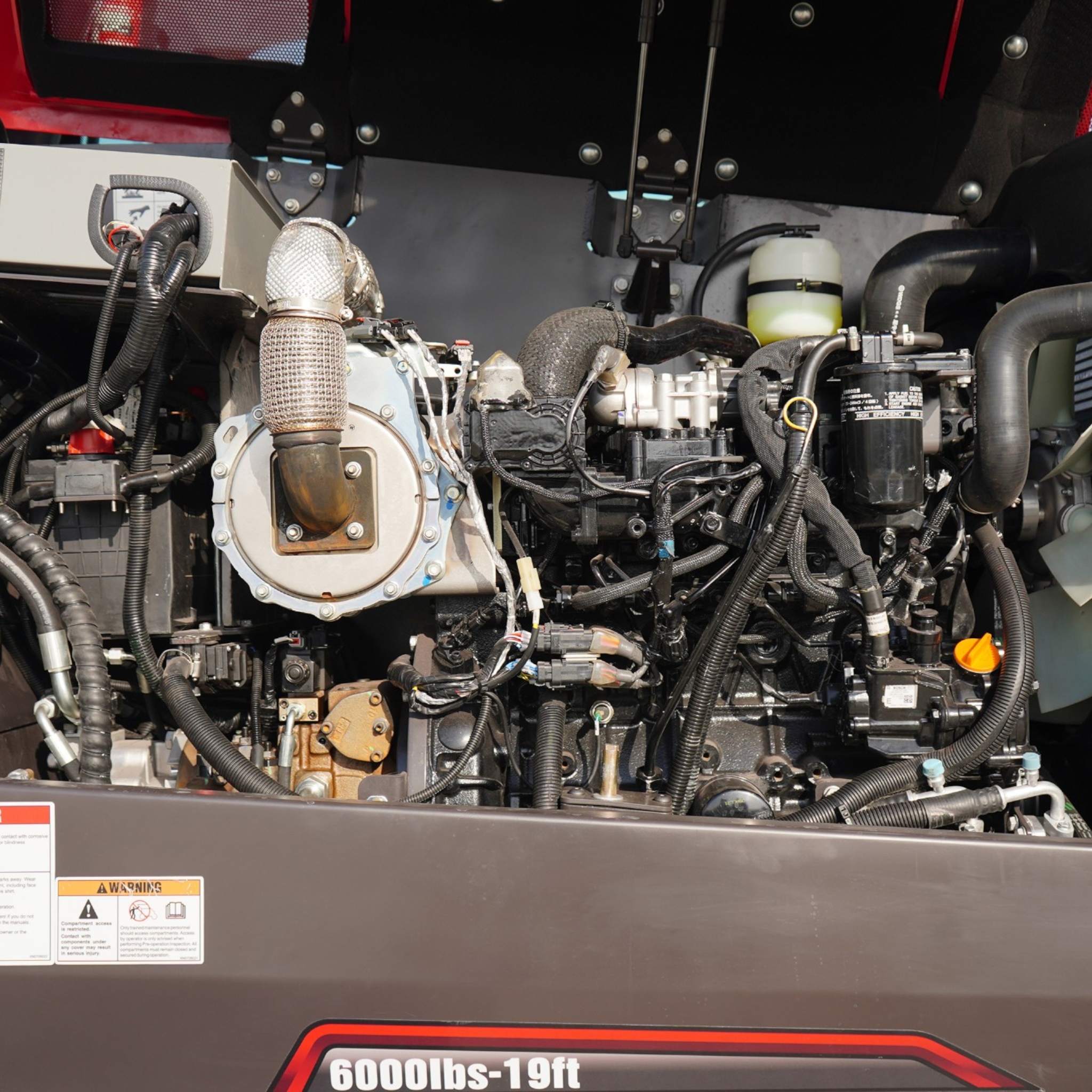 Open truck engine bay with exposed hoses, metal components, and wiring; a '6000 lbs - 19 ft' label is visible at the bottom edge.