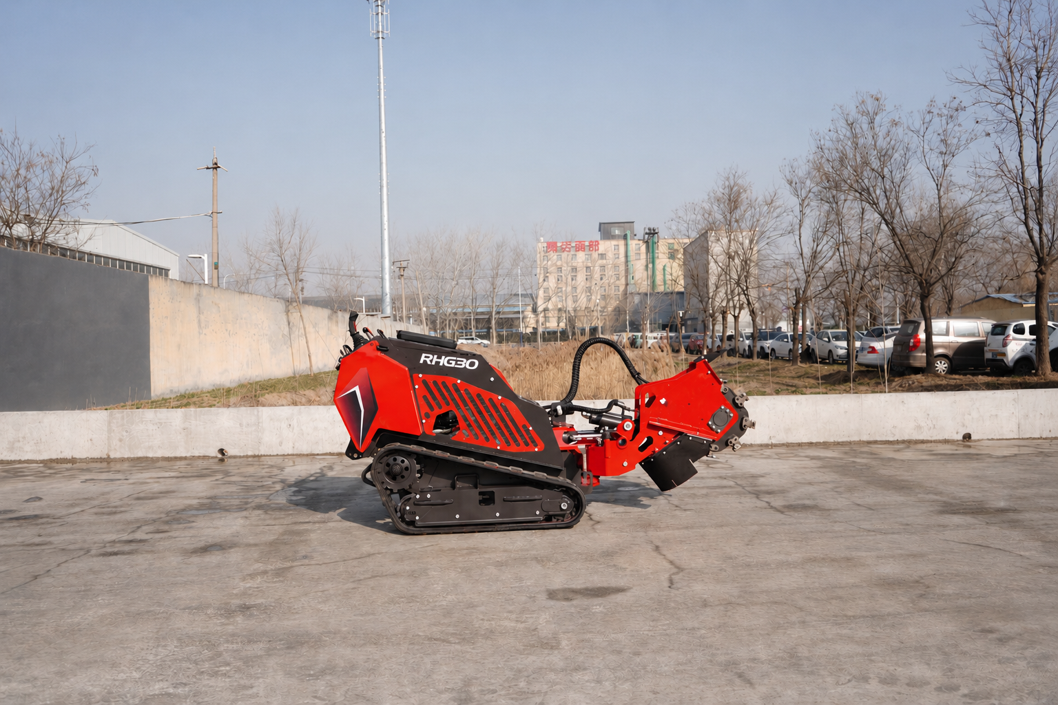 Red tracked industrial machine labeled RHG30 on a concrete lot with leafless trees and parked cars in the background, showcasing its cutting attachment.