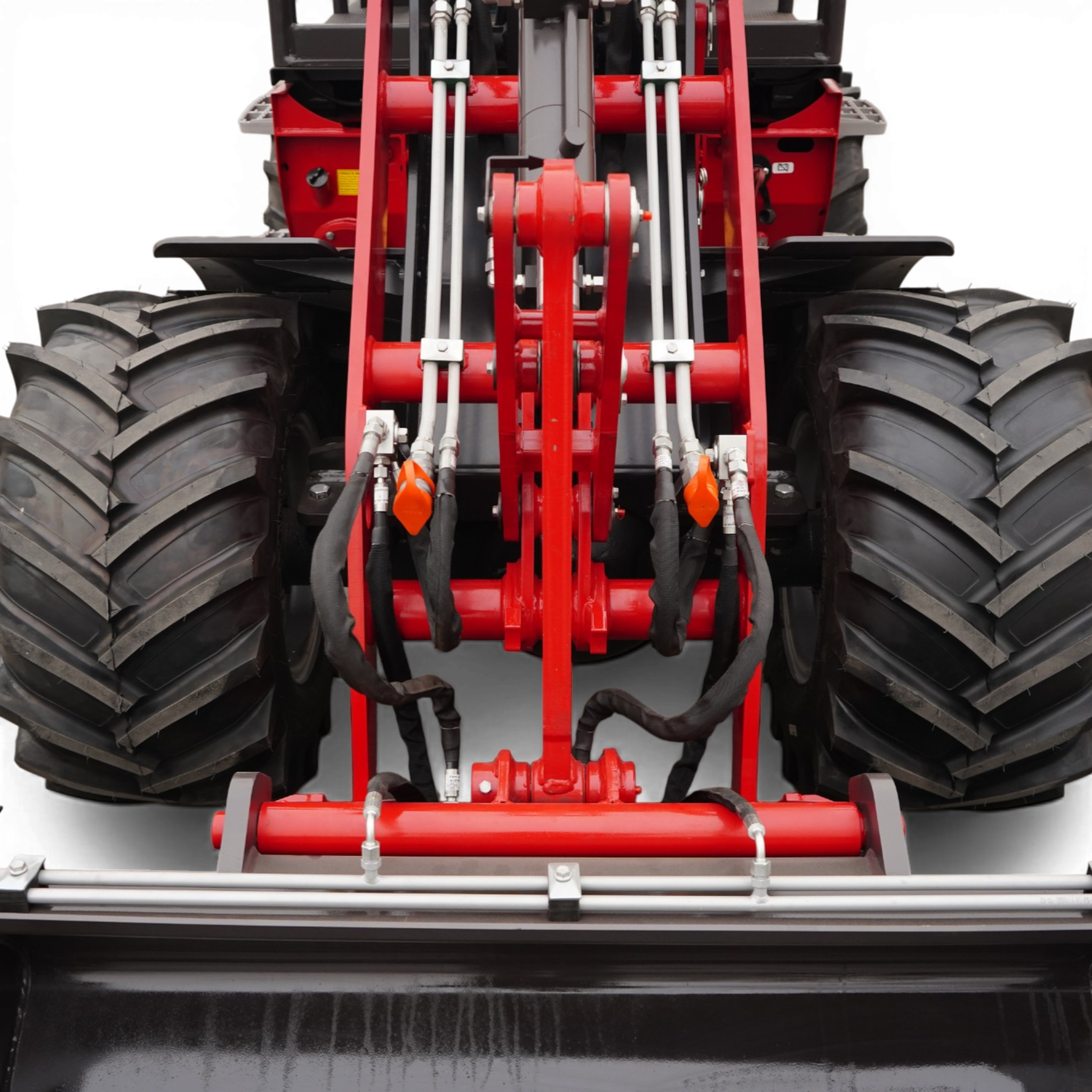 Close-up view of red industrial machinery with hydraulic hoses and large off-road tires on both sides