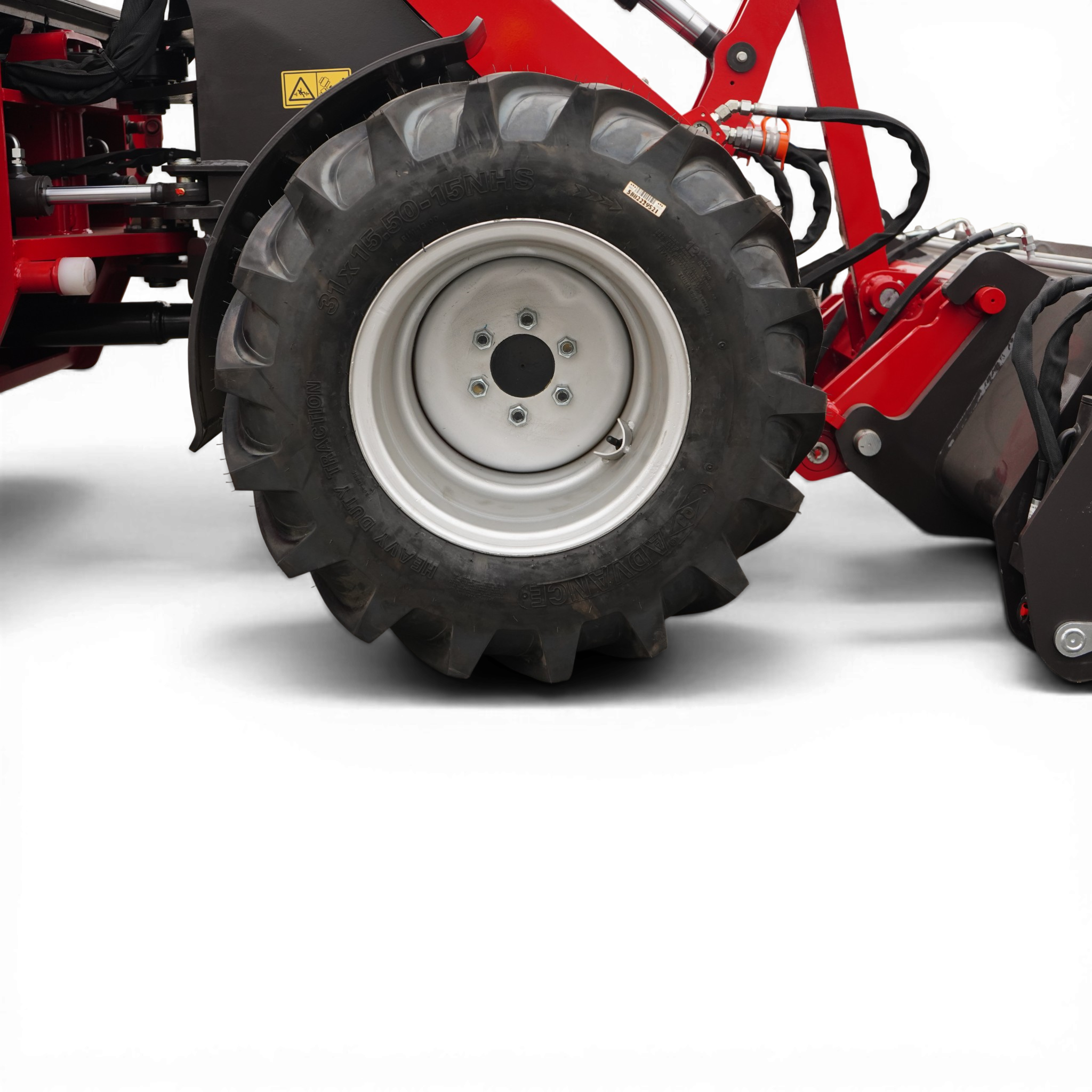 Close-up of a large tractor tire with deep treads and a silver hub, part of red agricultural machinery nearby.
