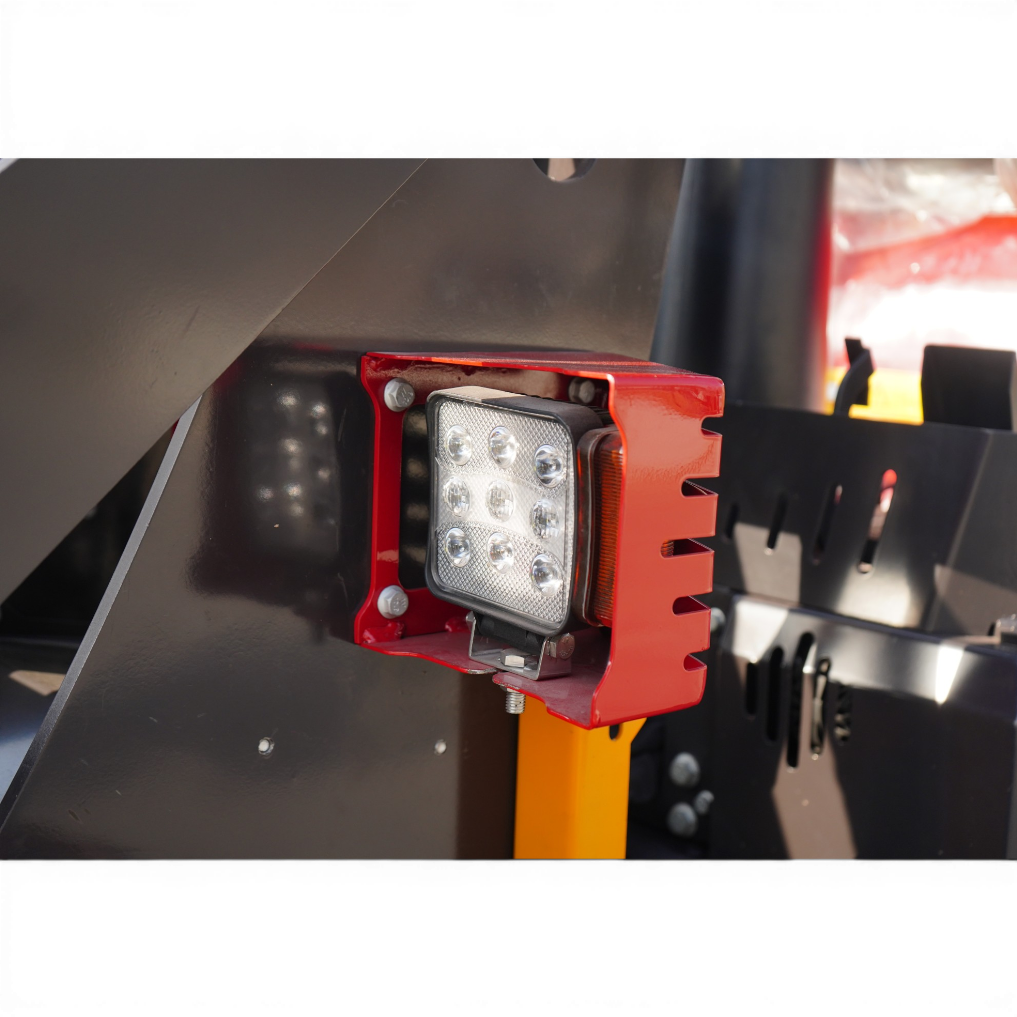 Red mounting bracket holding a rectangular multi-LED light against a dark metal surface, part of industrial equipment